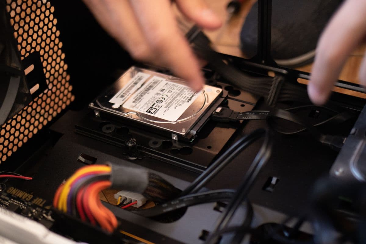 Hands installing a hard drive upgrade in a PC case