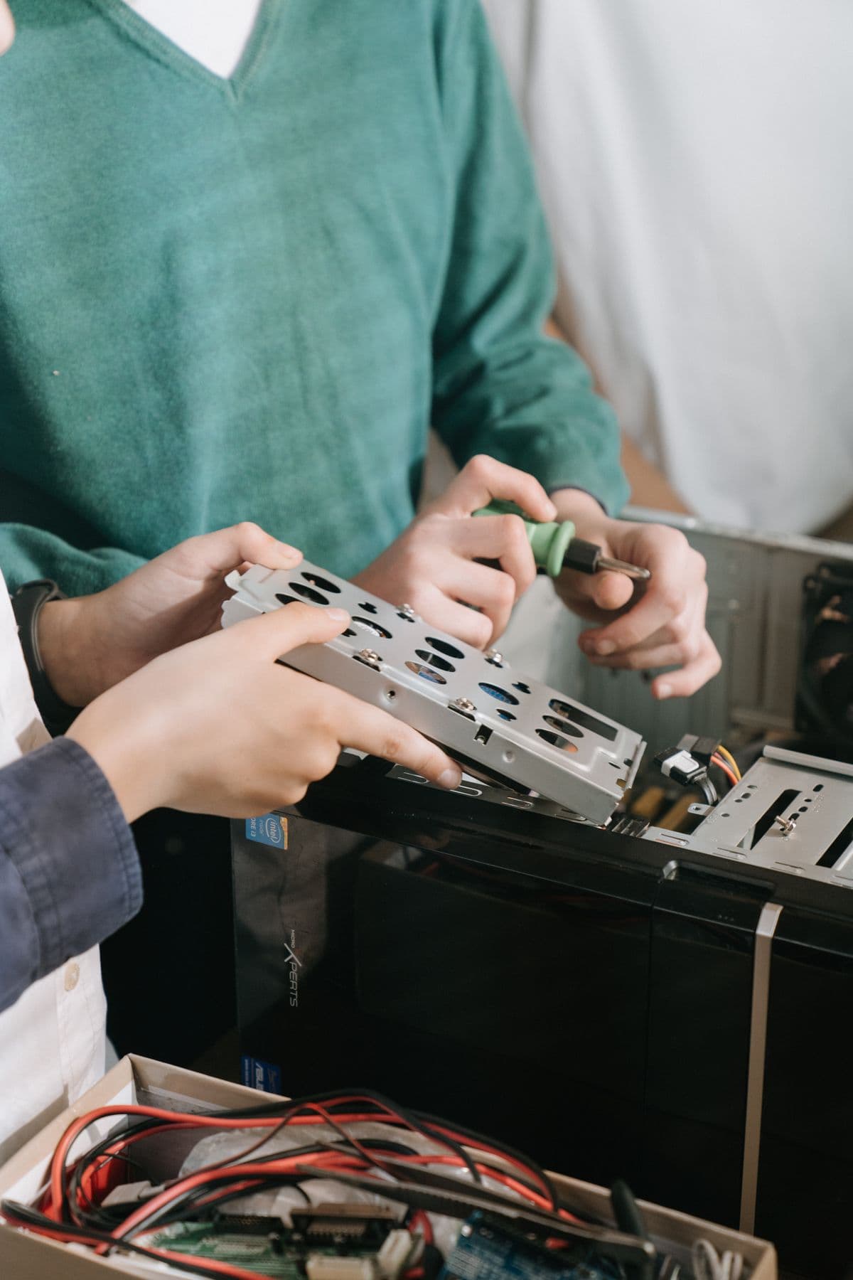 Technicians repairing computer hardware with screwdrivers