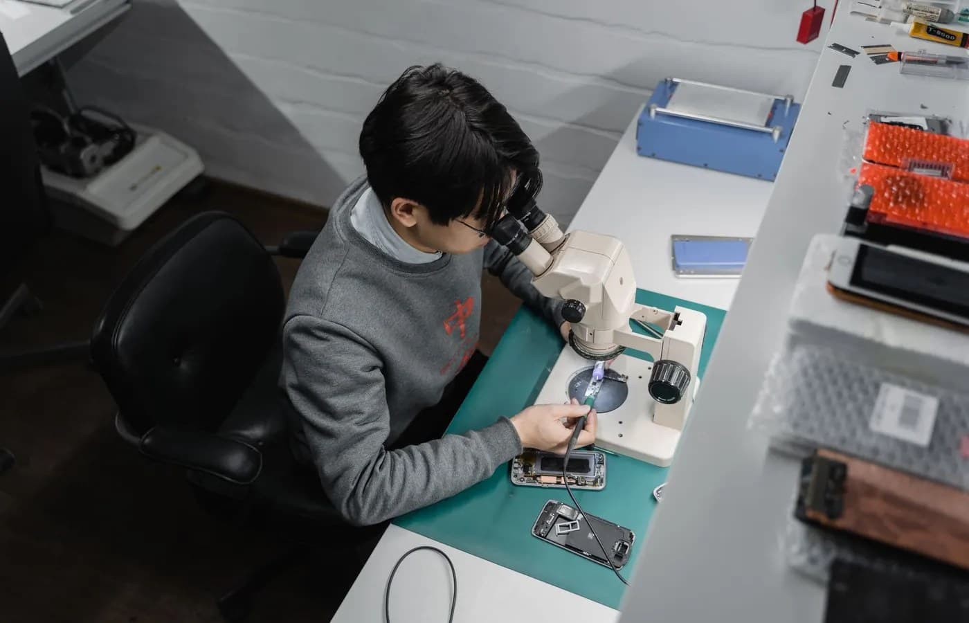 Mobile phone technician completing precision component repair under a microscope