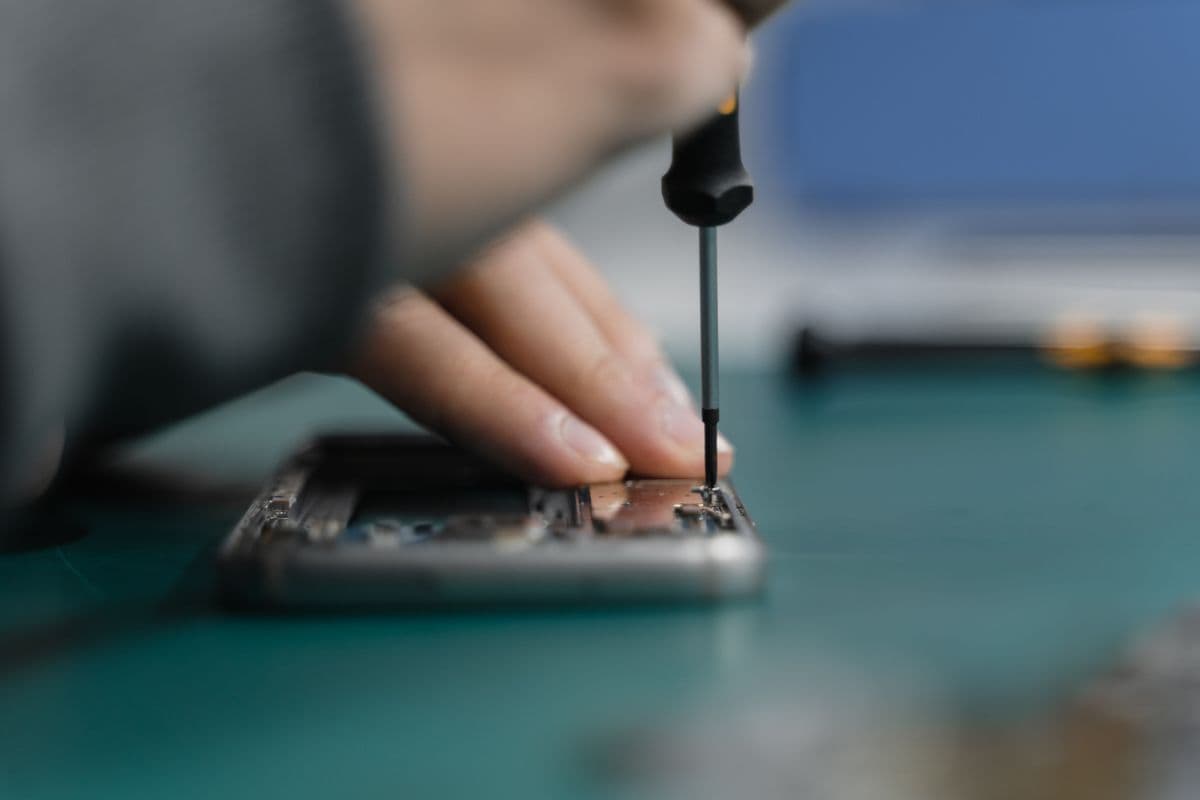 Technician unscrewing a smartphone frame during repair